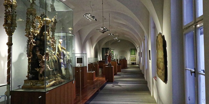 Interior of the Tyrolean Folk Art Museum featuring traditional wooden furniture, regional costumes, and rustic alpine décor.