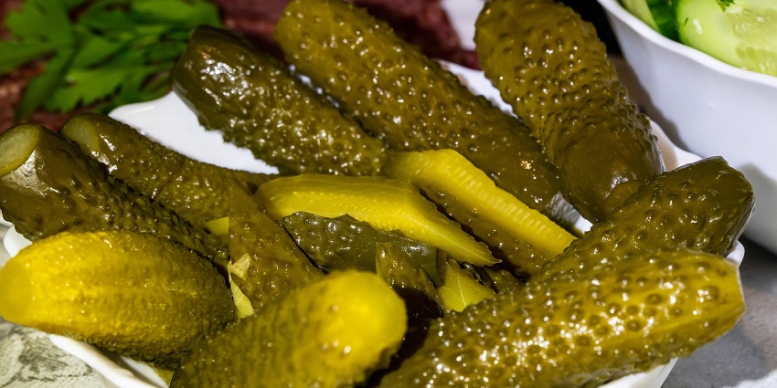 Image of a plate of pickles resembling the brinjal pickle with onions and mustard seeds.