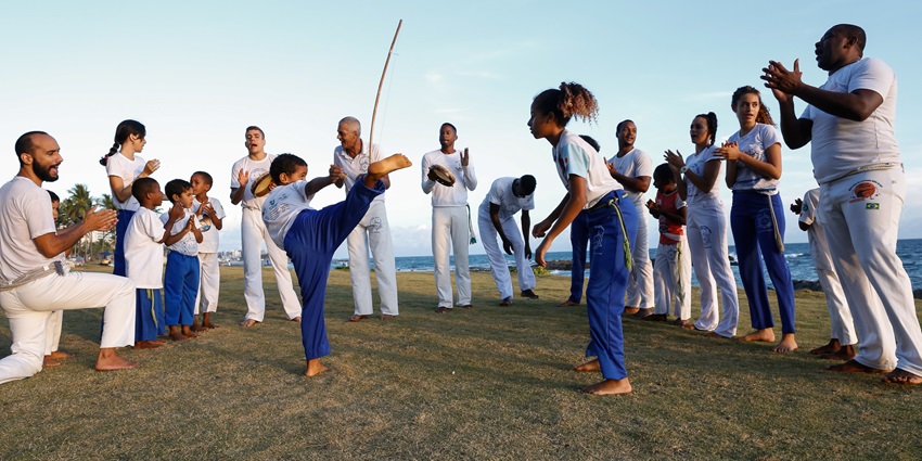 Capoeira Roda at the beach with martial artists performing in a circle on the sand