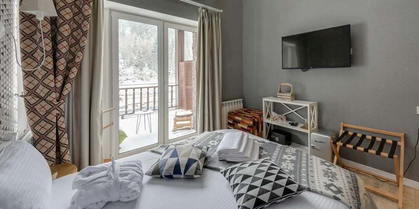 An image showing a hotel bedroom with a neatly made bed and modern interior design.