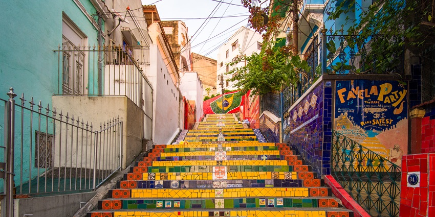Mosaic-covered staircase illuminated by streetlamps, with vibrant tiles from around the world and a quiet, romantic ambiance.