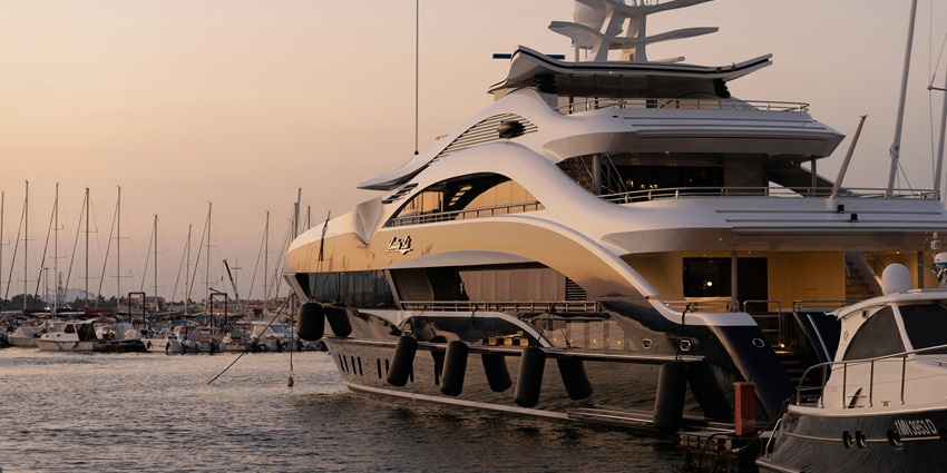 Image of a Yacht sailing into the water, adorned by sunset hues.