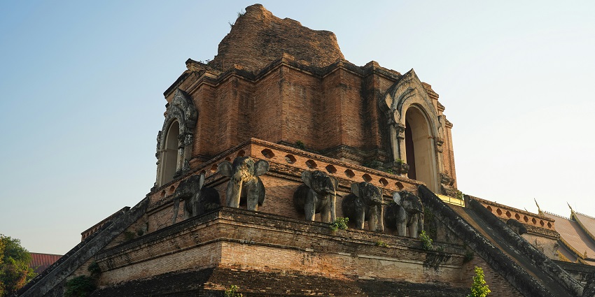 Wat Chedi Luang with large windows and a flat roof stands under a clear blue sky
