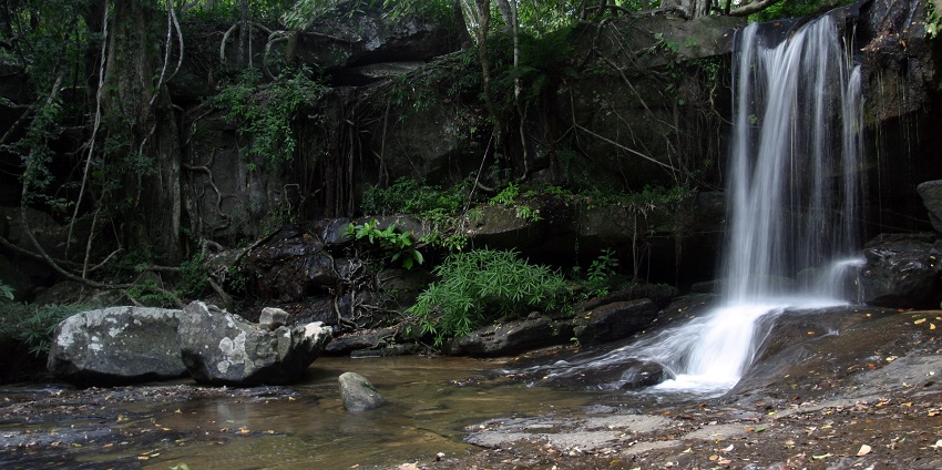 Picturesque view of Kbal Spean - Waterfall surrounded by lush greenery and rocks around the waterfall