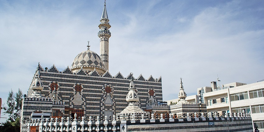 An image showing the black and white patterned exterior of Abu Darweesh Mosque on a hilltop.