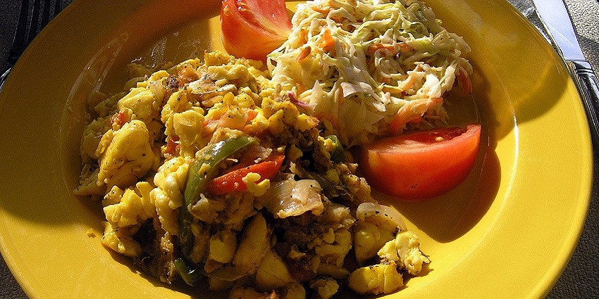 A serving of Ackee and Saltfish with boiled green banana, coleslaw and dumplings.