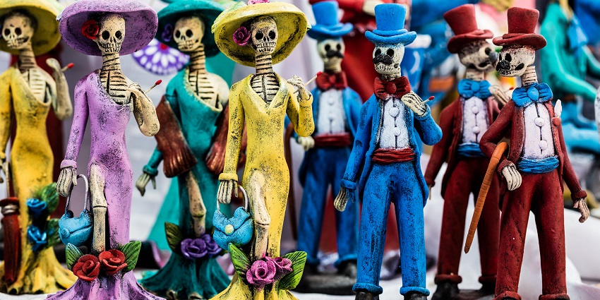 Multiple colourful figures of skeletons inspired by José Guadalupe Posada placed on a display