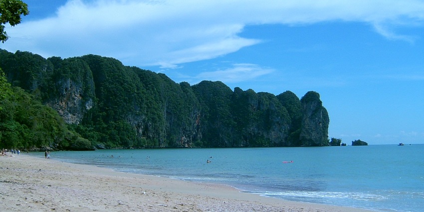 Ao Nang Beach shoreline with long-tail boats parked, and sunset casting golden hues.