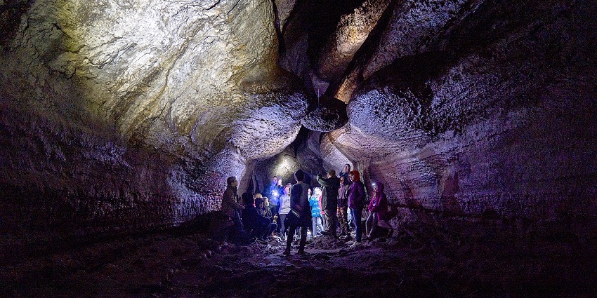 an image of a hiker walking along the lava-created Ape Cave in Washington State