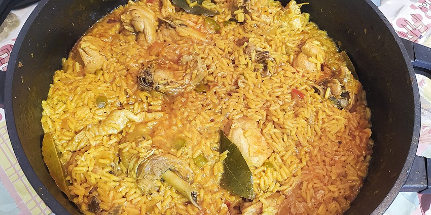 A plate of Arroz con Pollo with shredded chicken, rice, and vegetables