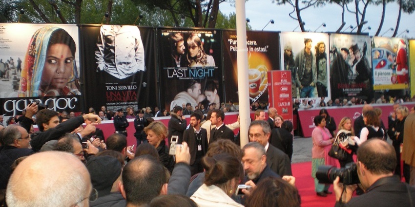 A picture from the celebrations at a film festival with posters of various movies in the background