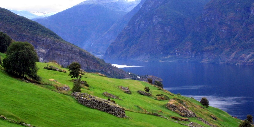 Hiking trail through Aurlandsdalen Valley in Norway with rocky terrain, a river, and distant waterfalls.