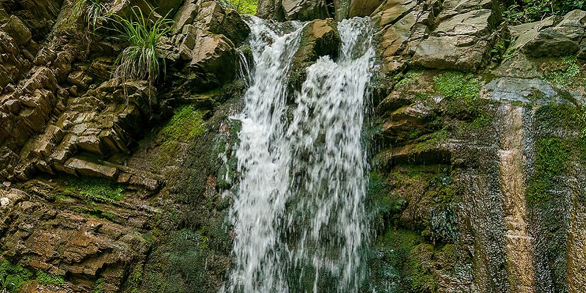 Close view of a waterfall crashing down rocky cliffs with mist and flowing white water
