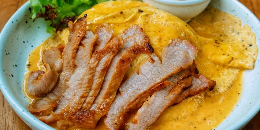 An image of bai sach chrouk, a dish with grilled pork over rice with pickles, one of the best food in Cambodia.