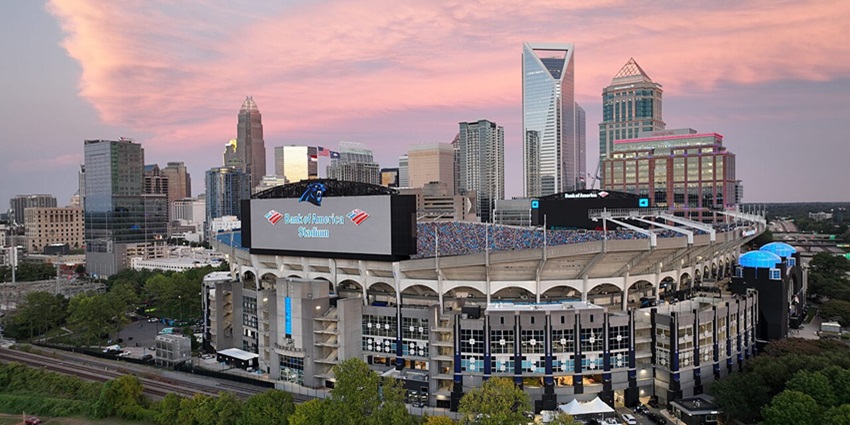 Bank of America stadium with multiple signages, distant cars and crowd in the stadium stands