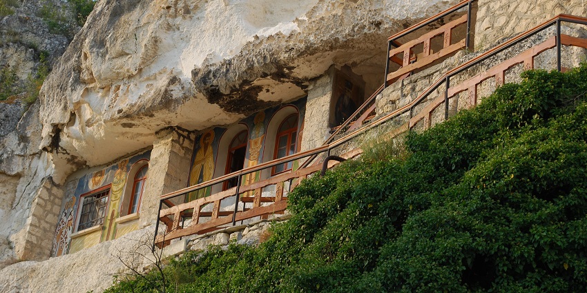 A rock-hewn monastery perched on a cliffside with scenic views and a peaceful vibe.