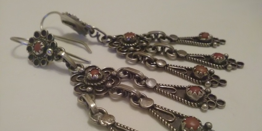 Traditional Bedouin silver necklace with detailed patterns and coins on a fabric backdrop, things to buy in Oman.