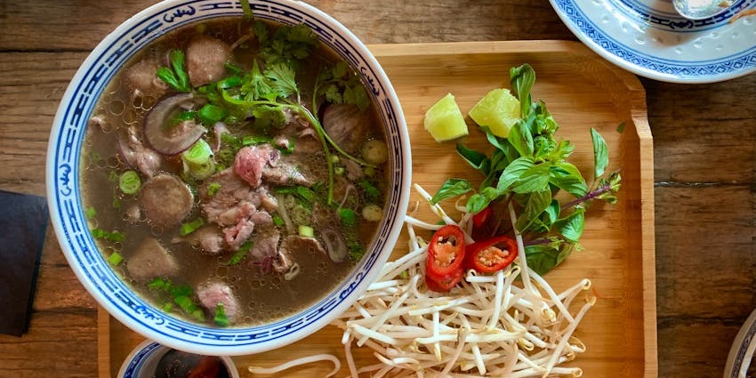 An image showing a bowl of soup placed on a wooden tray, similar to traditional black soup.