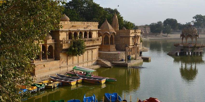 Tourists enjoying a boat ride on Gadisar Lake, with stunning reflections in the water.
