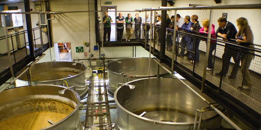 Bartender pouring beer from a tap into a glass with brewing tanks in the background in Arizona.