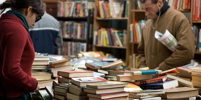 Books stacked on shelves in a softly lit bookstore with a relaxed, vintage atmosphere.