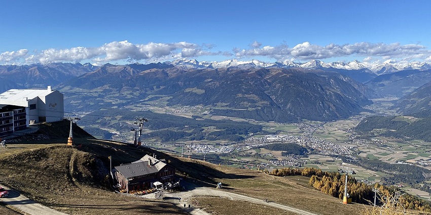 Bruneck from above with wires connected, distant small buildings and hills in the back