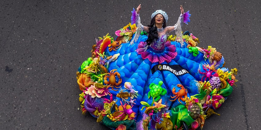 A gleeful lady with a vibrant costume dances on the street to entertain the passers-by.