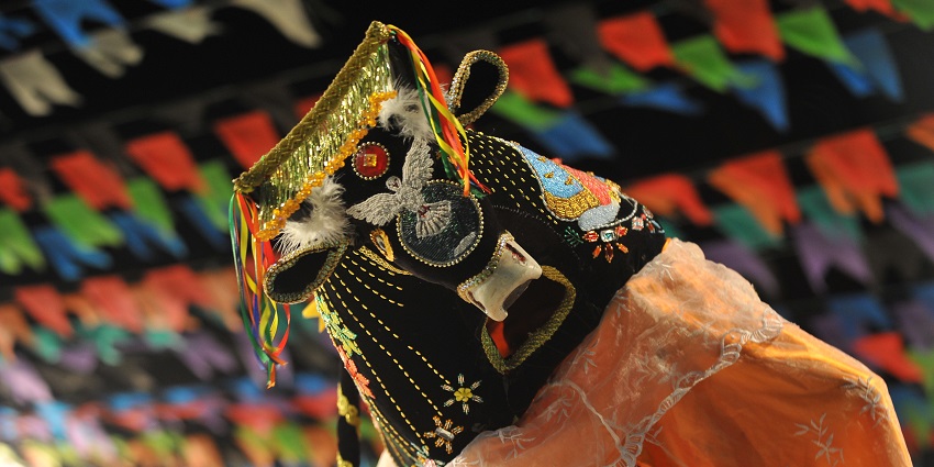 A puppet decorated in vibrant and designer clothing with colourful decorations in the back