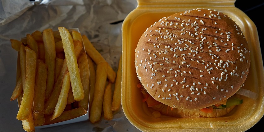 An image of a burger with lettuce, tomato, melted cheese and BBQ sauce in a brioche bun.