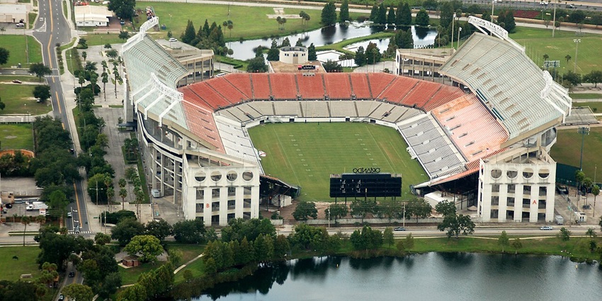 Stadium from above with multiple waterbodies nearby, stadium lights, red and white stands