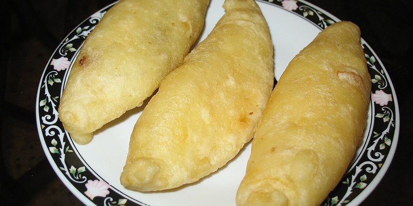 An Image of a crispy fried Carimañolas stuffed with ground beef on a serving plate.