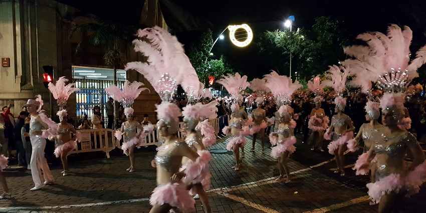 Dancers in sparkling costumes and feathered headdresses light up the night parade.