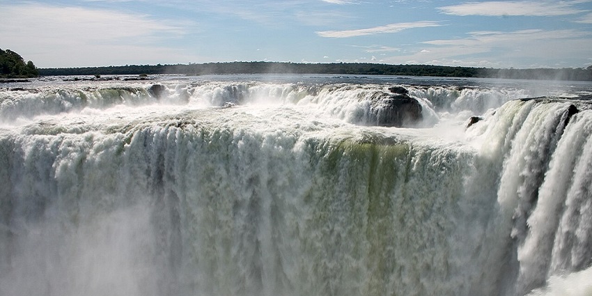 Powerful waterfalls are crashing down rocky cliffs with mist rising into the air.