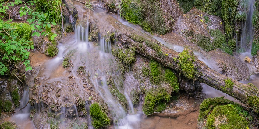 Cascade de Saunhac waterfall with water flowing over rocks, surrounded by lush greenery
