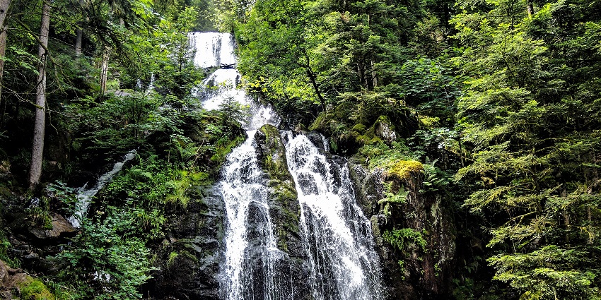 Cascade de Tendon Waterfall flowing down with low pressure from the rocky cliffs.