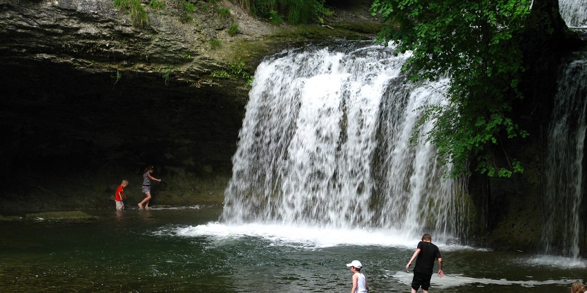 People dipping their feet in the pool created by the cascade du Hérisson’s moderate flow