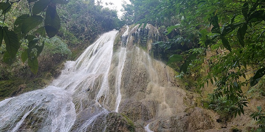 Catarata Bayoz with water flowing on the rocky surface and surrounded by greenery
