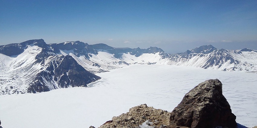 Snow-covered Changbai Mountain with dark rocks and volcanic valleys in China.