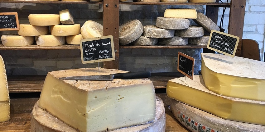 A selection of French cheeses on display in a shop, one of the popular things to buy in Paris.