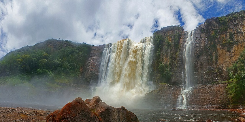 A wide view of Chinak Merú shows its towering water streams with a background of cloudy sky