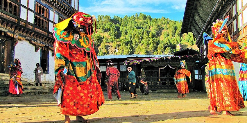People in traditional dress at a festival in Chumey Valley with hills in the backdrop.