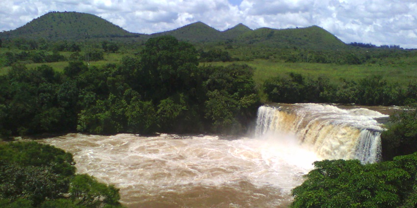 Chutes de la Vina Waterfall cascades amid a lush forest and mountain backdrop in Cameroon.