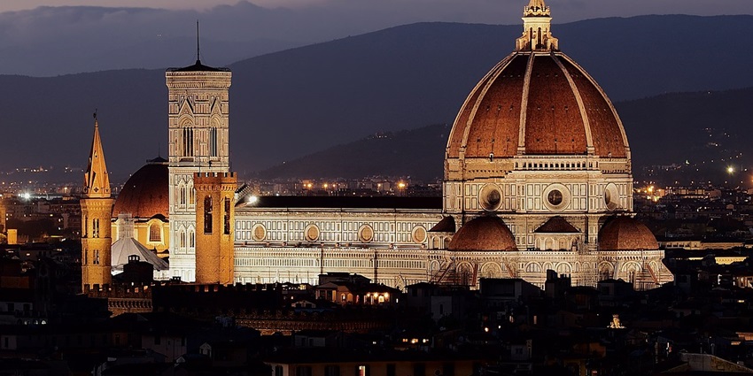 An image of Florence Cathedral illuminated at night, showcasing its majestic dome.