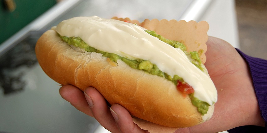 An image of Completo, a large hot dog topped with tomato and mayonnaise, the best food in Chile.