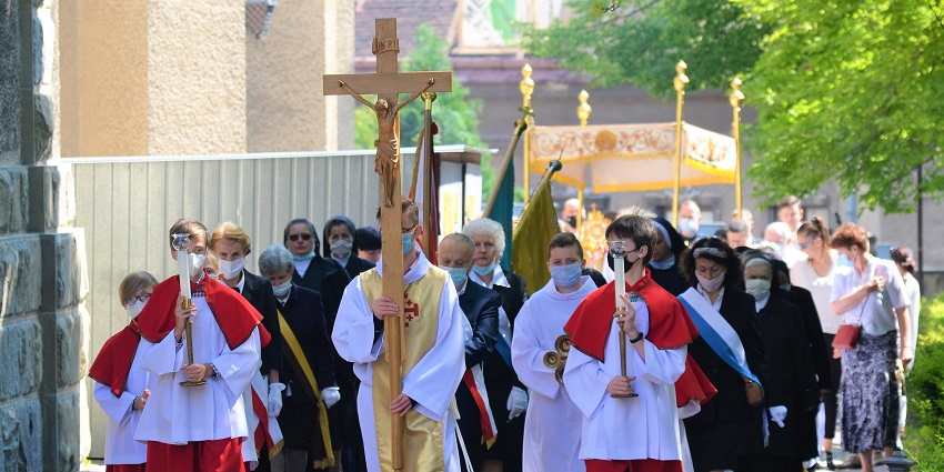 A group of attendees wearing religious dresses and carrying cross parades during Corpus Christi