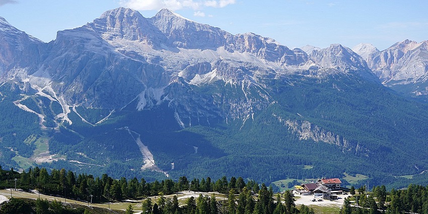 Cortina d’ampezzo with green trees, distant small houses and mountains in the back
