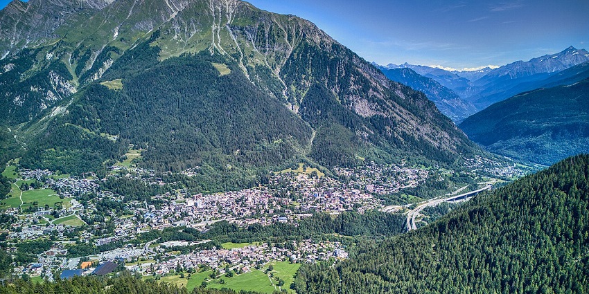 Courmayeur from above, with distant houses and buildings surrounded by green hills