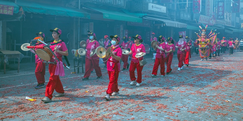 A lively parade with colorful costumes, dancers, and decorated floats moving through a festive crowd.