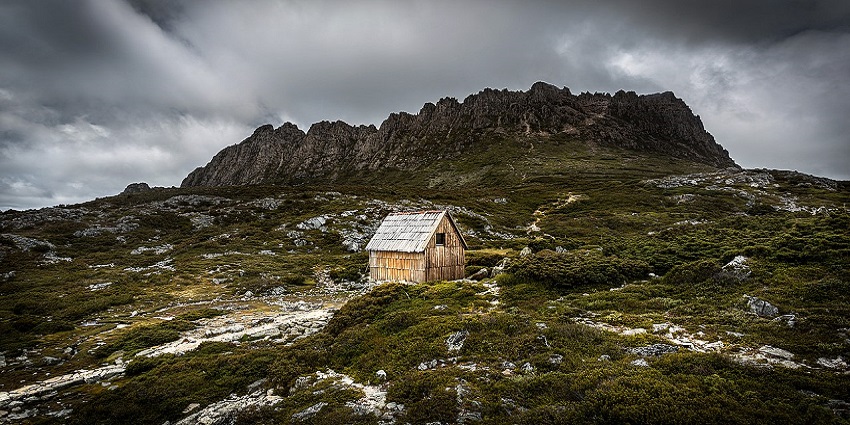 A hut against the backdrop of the huge and beautiful Cradle Mountain in Australia.