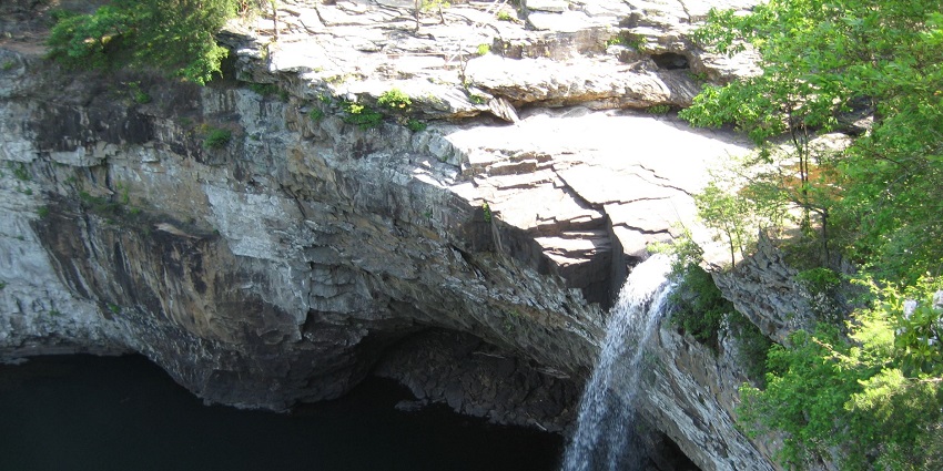 Desoto Falls flowing in low pressure from a cliff, forming a cave above the waterbody